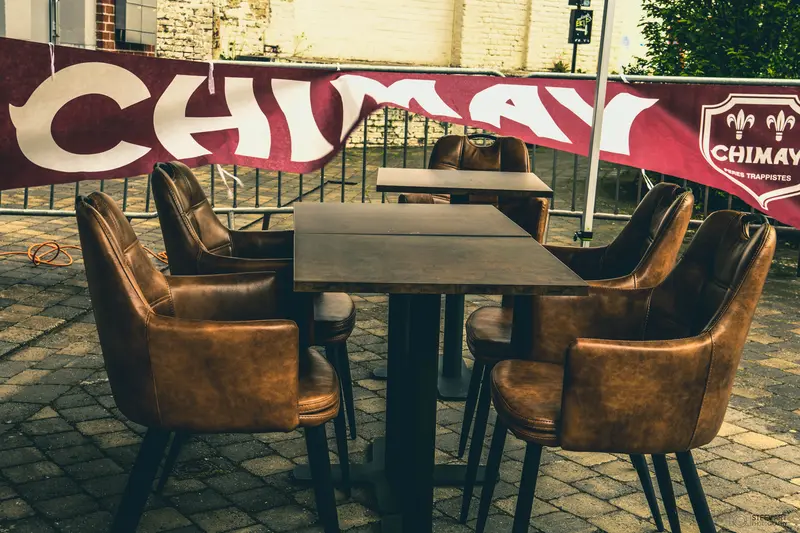 Fauteuils en cuir et tables sur la terrasse, bannière Chimay
